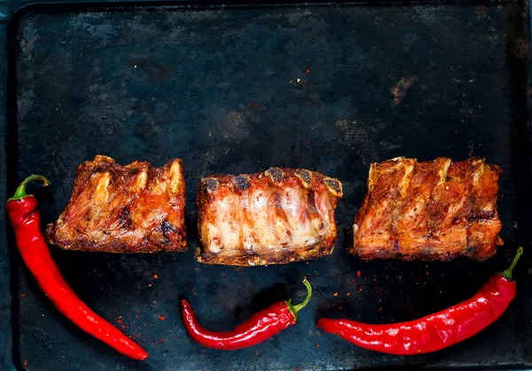 Spicy hot grilled spare ribs from BBQ served with  hot chili pepper on vintage rusty metal background. Banner.Top view,copy space — Stock Photo, Image