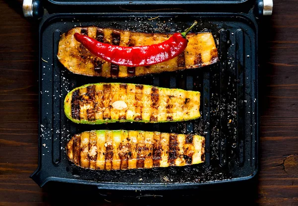Zucchine piccanti alla griglia e melanzane calde, cotte su una griglia elettrica. Bandiera. Il concetto di alimentazione sana e cibo delizioso . — Foto Stock