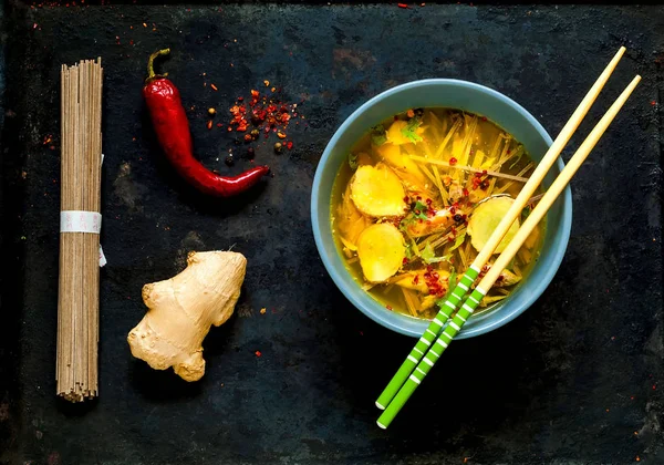 Soupe légère dans un style asiatique avec nouilles au sarrasin Soba et saumon dans le bol bleu avec baguettes sur fond noir en vieux métal. . — Photo