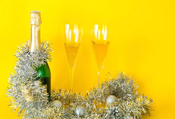 Brillante decoración de Navidad. Copas llenas y botella de champán decorada en tema festivo sobre fondo amarillo, concepto de vacaciones de Año Nuevo, primer plano, espacio para copiar — Foto de Stock
