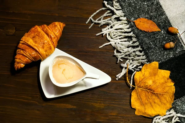 Kreativa keramiska kopp kaffe med mjölk och croissant på trä bakgrund med pläd, begreppet hemtrevnad och värme. Kopia utrymme, närbild — Stockfoto