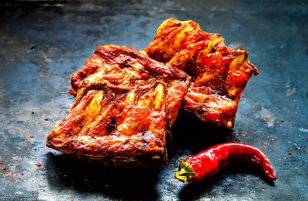 Spicy hot grilled spare ribs from BBQ served with  hot chili pepper on vintage rusty metal background. Banner.Top view, copy space, close up — Stock Photo, Image