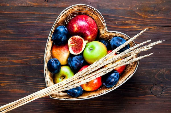 Äpplen, plommon och fikon i halm vas i form av hjärta på trä bakgrund, ovanifrån, ekologisk matkoncept, kost, detox mat. Platt låg. Kopiera utrymme. — Stockfoto