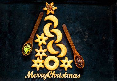 Noel ağacı kurabiye ve tahta kaşıklar ile baharat siyah arka plan üzerine yaptı. Kavramı kutlama ve pişirme. Kopyalama alanı, portre, üstten görünüm 