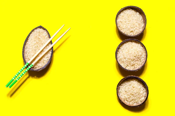 在有机椰子碗与筷子在几何纸背景上的大米。黄色时尚的颜色, 特写, 复制空间 — 图库照片