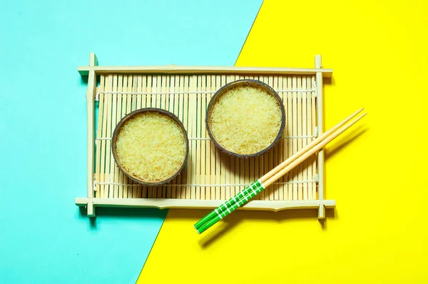 유기농 코코넛 기하학적 종이 바탕에 젓가락으로 그릇에 쌀. 노란색과 청록색 유행 색상, 복사 공간을 가까이 — 스톡 사진