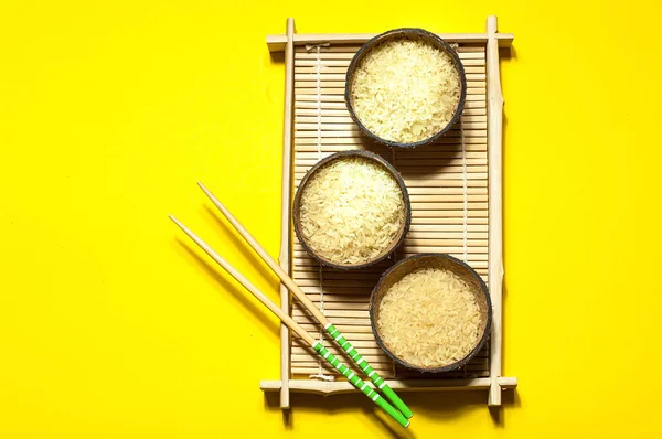在有机椰子碗与筷子在几何纸背景上的大米。黄色时尚的颜色, 特写, 复制空间 — 图库照片