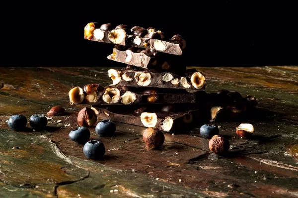 Schwarze Schokolade mit Nüssen und Blaubeeren auf dunklem Hintergrund. Kopierraum, Nahaufnahme — Stockfoto