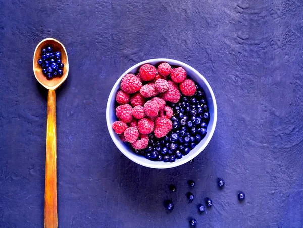 Hallon och blåbär i blå skål på blå bakgrund. Berry plocka, ekologisk matkoncept. — Stockfoto