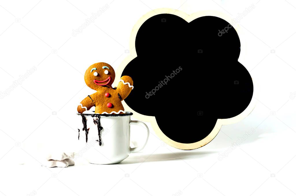 Gingerbread man in cup with hot chocolate and Slate board with marshmallow on light background. Copy space, close up