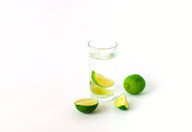 Bardak su ve beyaz zemin üzerine kireç. Detoks kavramı. Uzay kopyalayın, yakın çekim.