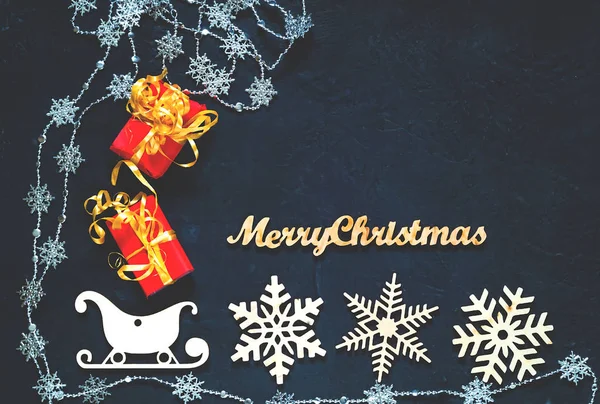 Décoratif en bois de Noël flocons de neige et traîneaux. Fond bleu foncé vacances avec guirlandes de Noël. Pose plate. Espace de copie, vue du dessus . — Photo
