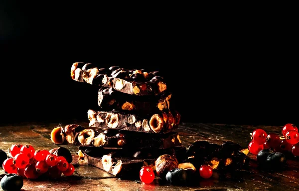 Schokoladenstücke mit Mandeln und Beeren auf dunklem Hintergrund. Kopierraum, Nahaufnahme — Stockfoto
