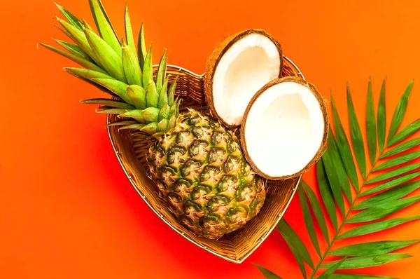 Frutas tropicales en canasta de mimbre sobre fondo coralino . — Foto de Stock