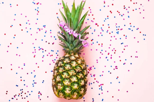 Ananas på rosa pastell trendiga bakgrund med konfetti och stjärnor. Festlig inramning för paketet. — Stockfoto