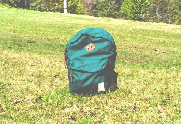 Weiblicher grüner Touristenrucksack auf Rasengrund in den Bergen. — Stockfoto