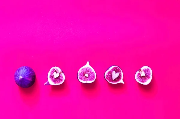 Plastik pembe bir arka plan üzerinde tüm ve dilimlenmiş incir yaratıcı düzeni. Son moda parlak renkler. 
