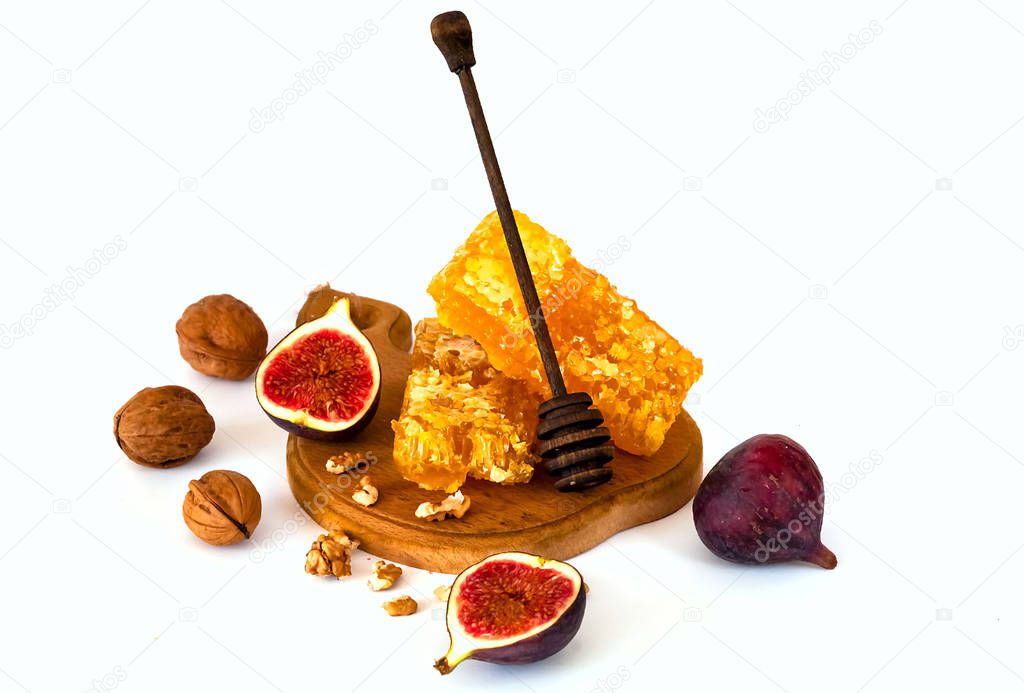Fresh figs with nuts and honey on a wooden board on a white isolated background. 