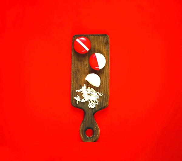Pequeno queijo redondo em pacote de parafina em tábua de madeira sobre fundo vermelho. Conceito de ano chinês . — Fotografia de Stock