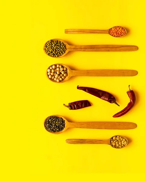 Ξύλινα κουτάλια και συστατικά σε κίτρινο φόντο. Η έννοια της βιολογικά προϊόντα δημητριακών. — Φωτογραφία Αρχείου
