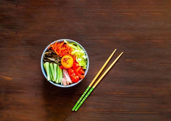 Plat traditionnel de la cuisine coréenne. Bibimbap avec boeuf, légumes et oeuf sur fond en bois . — Photo