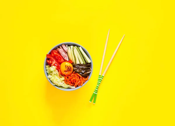 Prato tradicional da cozinha coreana. Bibimbap com carne bovina, legumes e ovo no fundo amarelo . — Fotografia de Stock