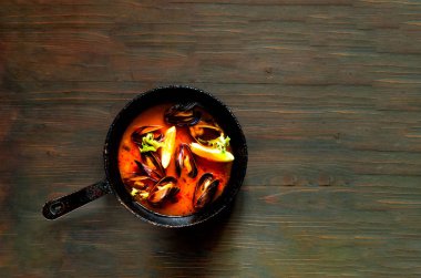 Ahşap arka plan üzerinde kırmızı Köri soslu midye.