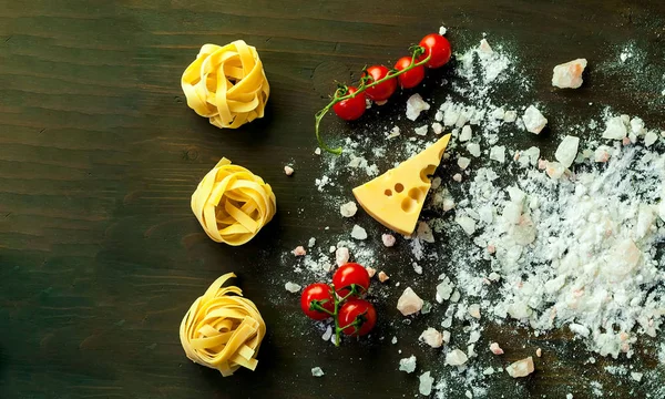 Voedsel achtergrond. Italiaanse fettucine pasta en roze zout op houten achtergrond. — Stockfoto
