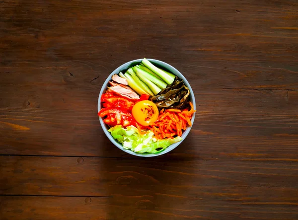Traditionell maträtt i koreanska köket. Bibimbap med nötkött, grönsaker och ägg på trä bakgrund. — Stockfoto