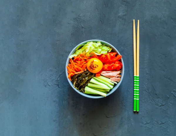 Traditionelles Gericht der koreanischen Küche. Bibimbap mit Rindfleisch, Gemüse und Ei auf blauem Hintergrund. — Stockfoto