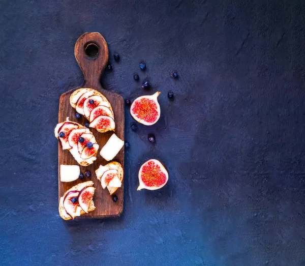 Smörgåsar med färska fikon, getost, honung och blåbär på trä kartong. — Stockfoto