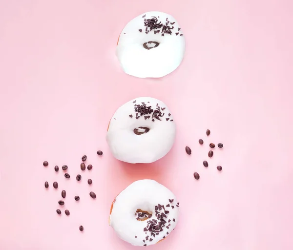 Fehér mázas fánk fekete csokoládé édességek rózsaszín háttér. — Stock Fotó