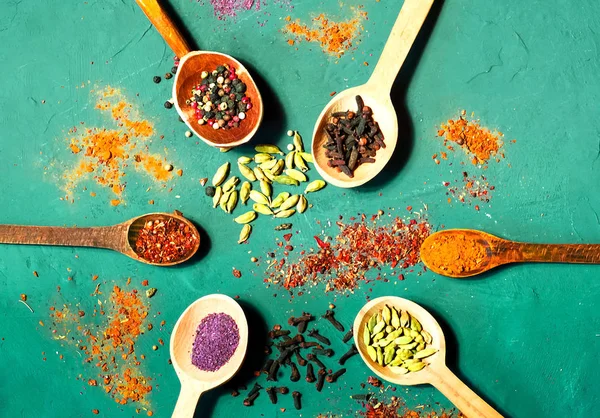 Wooden spoons with spices on blue background. Vegetarian food, healthy or cooking concept.