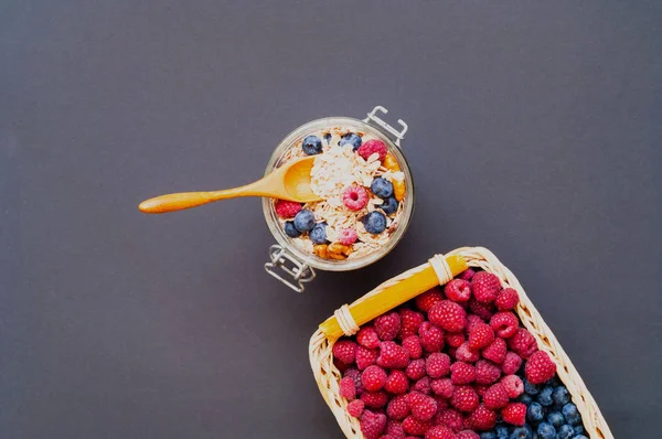 Müsli med blåbär och hallon i glasburk på svart bakgrund. — Stockfoto