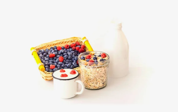 Beyaz arka plan üzerinde cam kavanozda yaban mersini ve ahududu ile Müsli. 