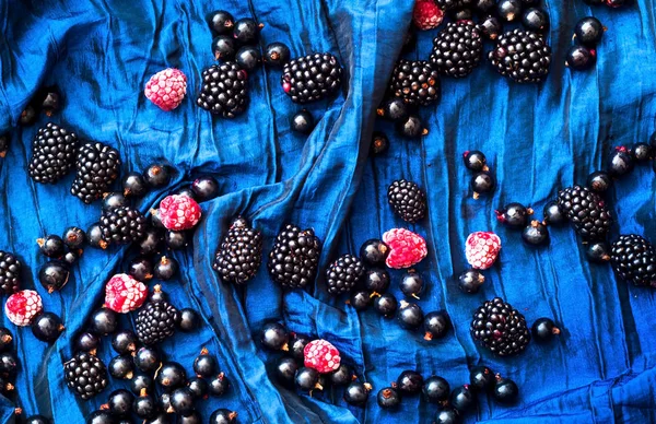 Creative food berry background. Blackberries and currants on a b