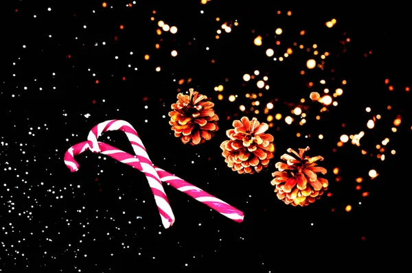 Παρελθόν Χριστουγέννων και Πρωτοχρονιάς. Καραμέλα ζαχαροκάλαμο και κουκουνάρια στο φόντο των γιρλάντες. — Φωτογραφία Αρχείου