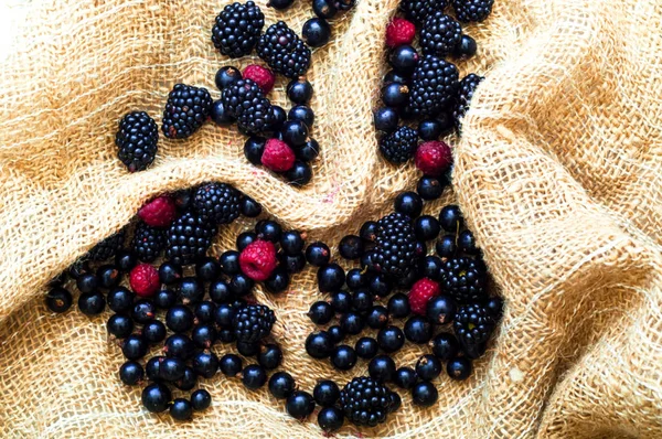 Creative food berry background. Blackberries and currants on burlap texture.