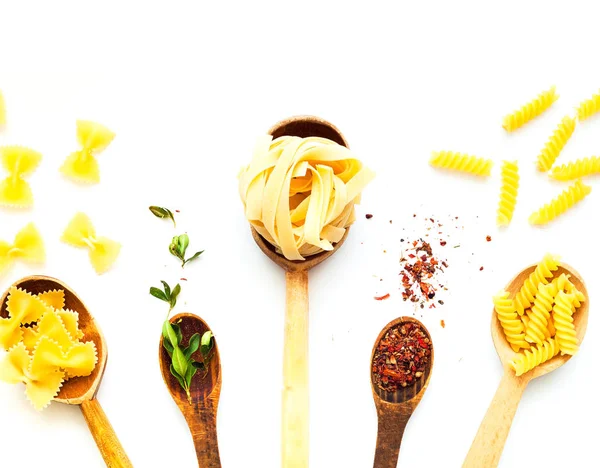 Houten lepels met pasta en specerijen op witte geïsoleerde achtergrond — Stockfoto