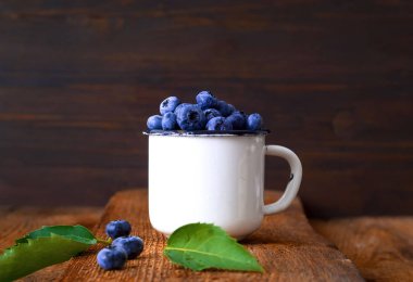 Eski ahşap tahtalar üzerinde vintage beyaz kupa yaban mersini. Organik gıda konsepti