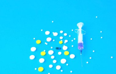 Mavi arka planda haplar ve tıbbi şırınga. İlaç reçete 