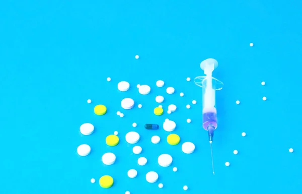 Pastillas y jeringa médica sobre fondo azul. Receta de medicamentos — Foto de Stock