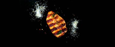 Grilled meat with spices on dark isolated background. Close-up
