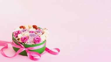 Gül tomurcukları ve pembe arka planda rengarenk kurabiyeler. Ulusal Pembe Gün. Şablon tebrik kartı veya tasarım modelleri..