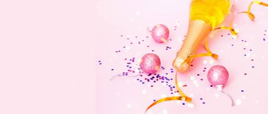 Pembe arka planda konfeti olan şampanya şişesi. Bulanık etki. Noel tasarımı için yaratıcı bir alan. Yakın plan.