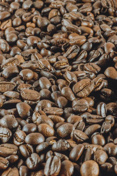 Background:a lot of coffee whole grains lies. Vertical toned photography