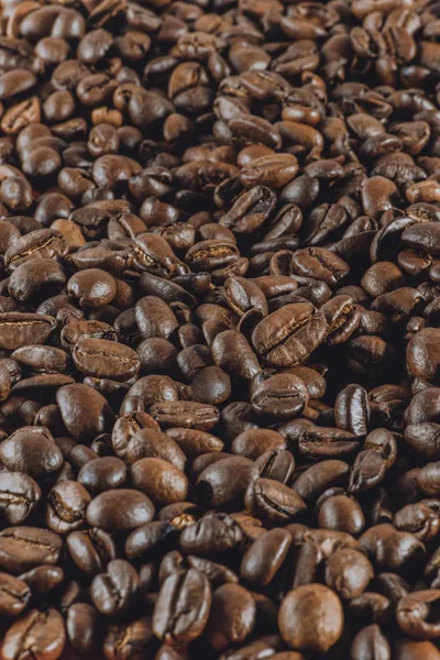 Background:a lot of coffee whole grains lies. Vertical toned photography