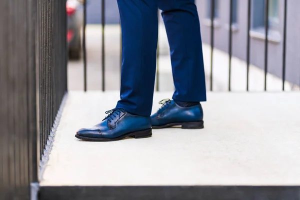 Men\'s feet in shoes. Fragment of the feet of a man in a blue suit and blue shoes on the porch of a house on the street.