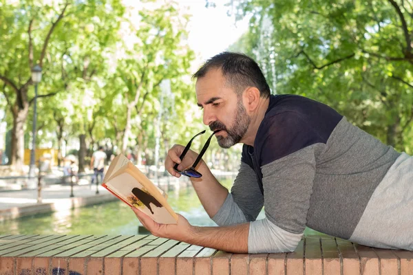 bir kitap okuma bir parkta yatan adam