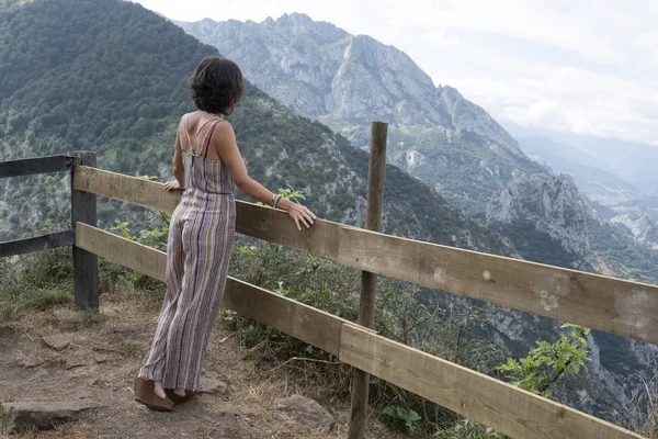 woman standing back on wooden railing in Asturian landscape